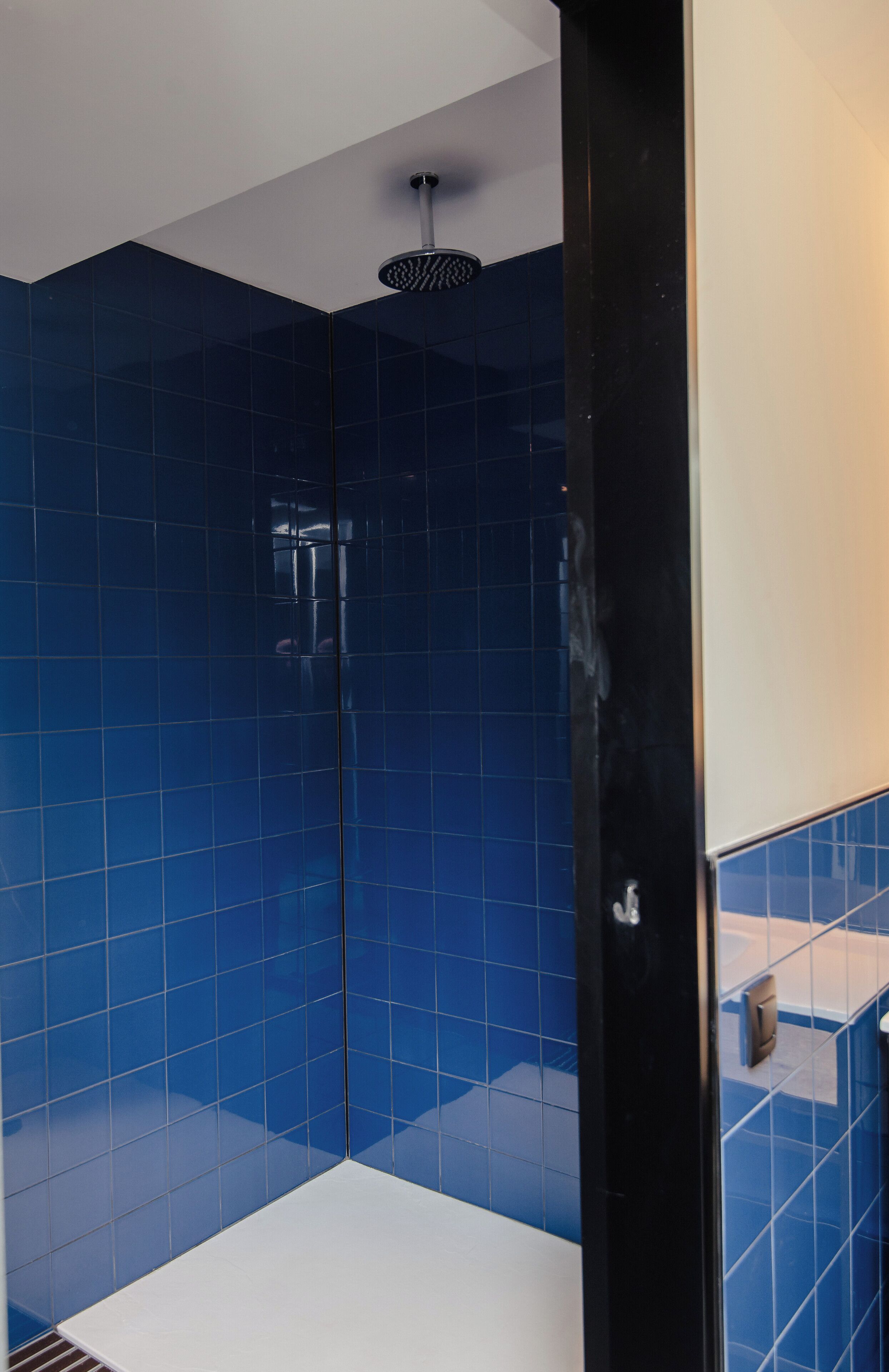 Een moderne badkamer met blauwe tegels en een zwarte douchecabine.