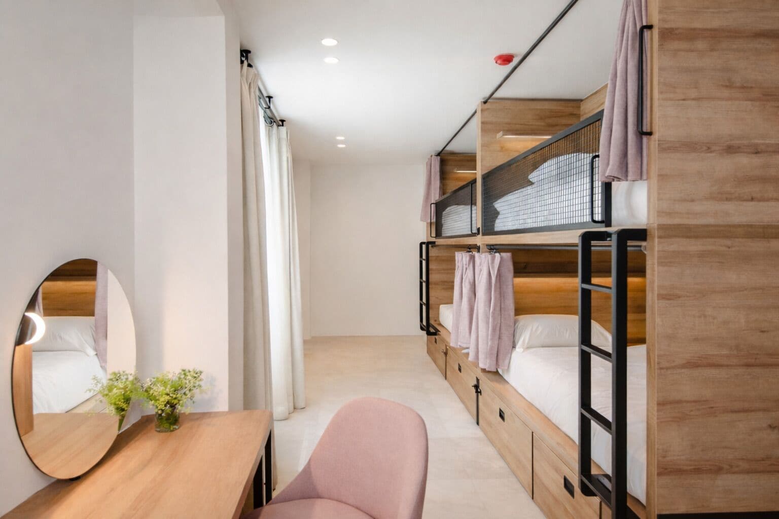 Une chambre avec un lit superposé, un bureau en bois, une chaise, un miroir et une petite plante.