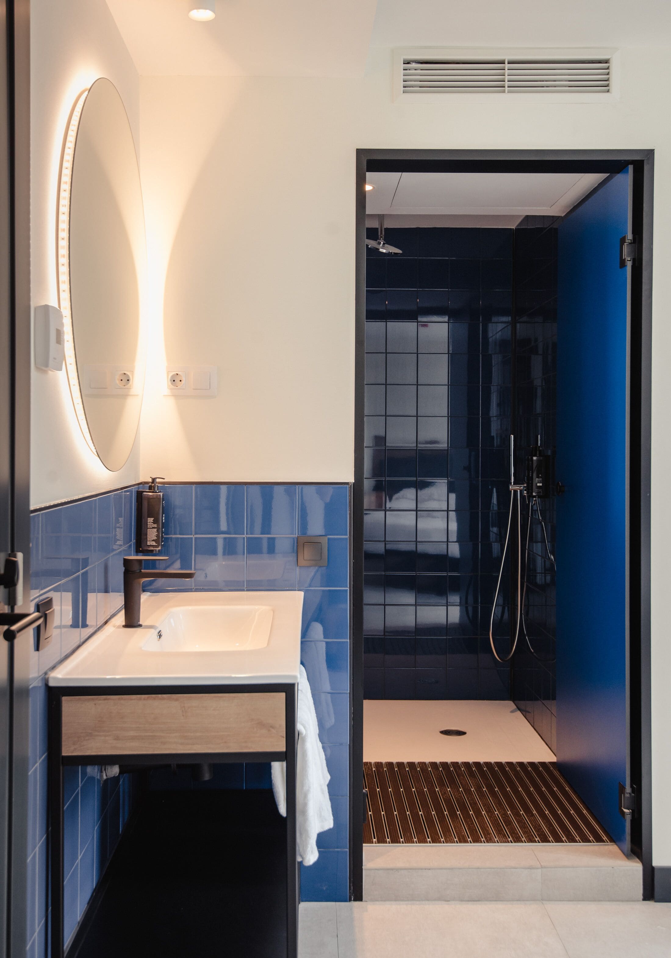 A modern bathroom with a sink, mirror, and shower.