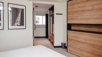 A bedroom with a bed, wooden wardrobe, and a framed picture on the wall.