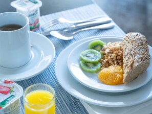 En frukostuppläggning med en tallrik mat, ett glas apelsinjuice och en kopp kaffe.
