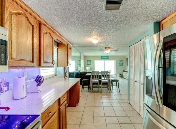 Enjoy cooking in this kitchen with a central island and seating, featuring a refrigerator and a ceiling fan.