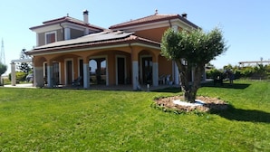 Une maison à deux étages avec un patio couvert et un petit arbre dans le jardin.