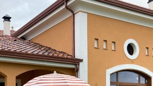 Une maison avec un patio, un parasol à rayures et une chaise longue.