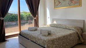 Une chambre à coucher avec un lit, des rideaux, un tableau et une vue sur la verdure à l’extérieur.
