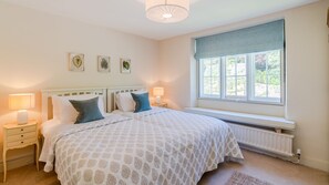 A bedroom with a bed, two bedside tables, a window with a view, and three framed botanical prints on the wall. - Colebrook Cottage - Blockley, Cotswolds (Blockley)