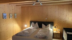 A wooden-paneled room with a bed, two bedside lamps, and a nightstand.