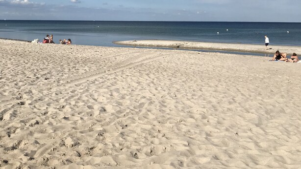 A sandy beach with footprints and a few people in the distance. - Ferienwohnung an der Ostsee (Hasselberg)