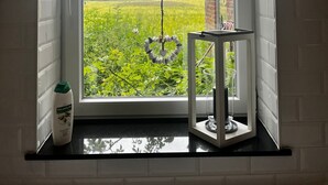 A kitchen with a window overlooking a green field. - Ferienwohnung an der Ostsee (Hasselberg)