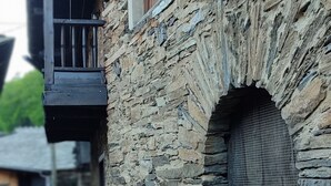 Un edificio de piedra con balcón de madera y una reja de metal.
