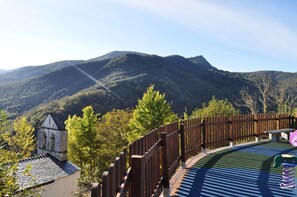 Vista panorámica de un paisaje montañoso con una cerca de madera y un pequeño edificio con un campanario.