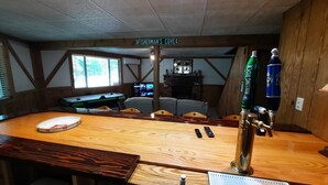 Et område med træbar, et skilt med teksten "FISHERMAN'S COVE", et billardbord og et fadølsanlæg mærket "ROLLING ROCK".