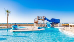 A swimming pool with a water slide and lounge chairs. - Luxury Direct Beachfront Corner Unit Lazy River-Waterslide-Walk to Restaurant's (Orange Beach)