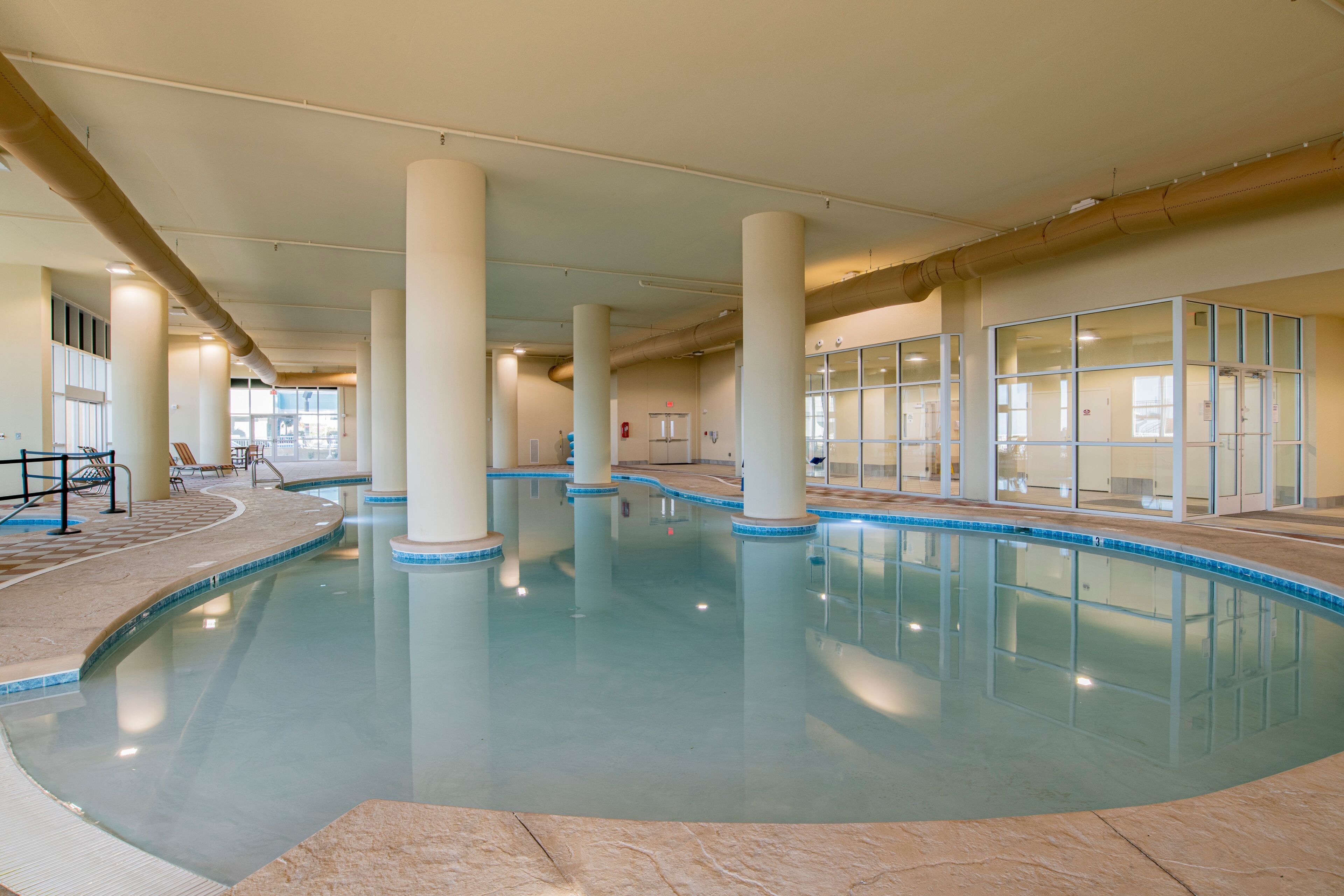 An indoor swimming pool with clear water, surrounded by columns and a tiled floor.