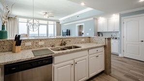 A modern kitchen with white cabinetry, granite countertops, and a dishwasher. - Luxury Direct Beachfront Corner Unit Lazy River-Waterslide-Walk to Restaurant's (Orange Beach)