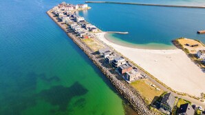 An aerial view of a coastal town with a long pier extending into the sea, a sandy beach, and buildings along the shore. - Land`s End - Blick auf die Freie Ostsee, Sauna, Wintergarten, Elektro Grill (Olpenitz)