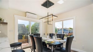 A dining area with a glass table, black chairs, and a modern pendant light.