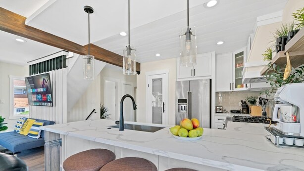A modern kitchen with a large island, bar stools, and a built-in refrigerator.