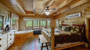 A cabin interior with a bed, a desk, a bench, and a view of the outdoors. - "Shine Valley #53" View for days (sevierville)