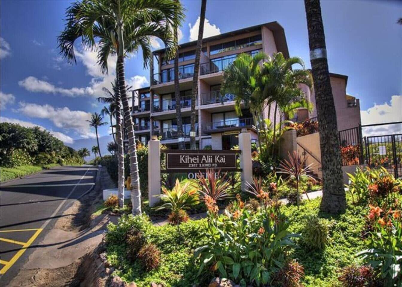 A hotel with a sign reading "Kihei Alii Kai" and a road in the foreground.