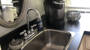 A kitchen with a stainless steel sink, a coffee maker, a dish soap bottle, and a decorative bowl. - Newly Constructed Second Floor Modern Studio Apartment Unit 2 ~ Sleeps 6 (Accomac)