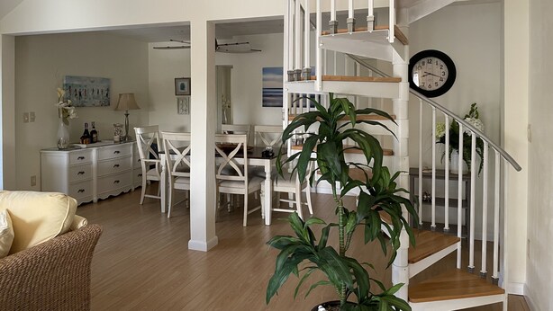 A spacious living area with a staircase, dining table, chairs, and a large potted plant. - Vacation home within walking distance to Bowman Beach (Sanibel)