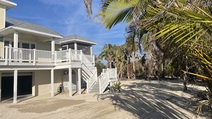 A beachfront property with a two-story house, a covered porch, and a staircase leading to a balcony. - Vacation home within walking distance to Bowman Beach (Sanibel)