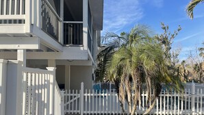 A two-story building with a white exterior, a balcony, and a white picket fence. - Vacation home within walking distance to Bowman Beach (Sanibel)