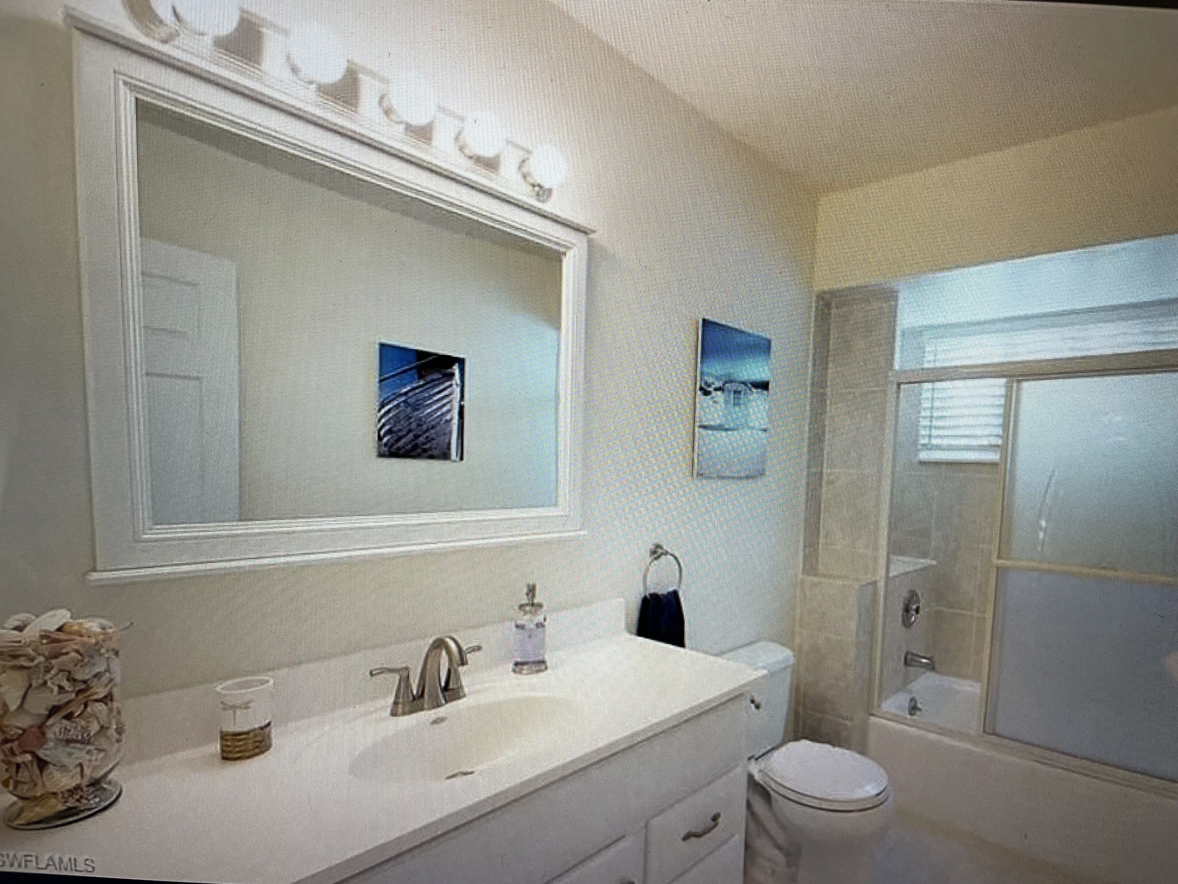 A bathroom with a large mirror, a sink, a toilet, and a shower.