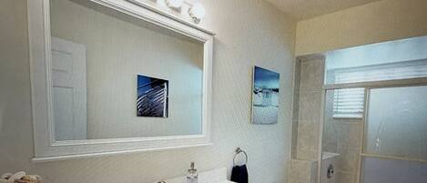 A bathroom with a large mirror, a sink, a toilet, and a shower.