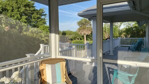 A covered porch with wicker chairs and a view of the surrounding greenery. - Vacation home within walking distance to Bowman Beach (Sanibel)