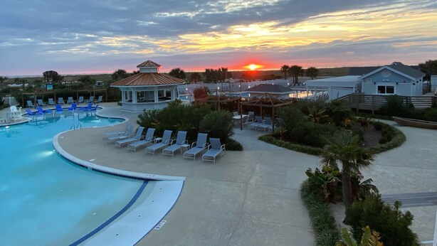 A resort pool area with lounge chairs, a gazebo, and a sunset view. - Charming Studio / Cottage in Marina BHI & Shoals Club Available (Bald Head Island)