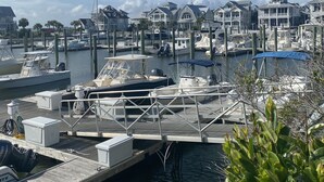 A marina with docked boats, a wooden dock, and waterfront houses. - Charming Studio / Cottage in Marina BHI & Shoals Club Available (Bald Head Island)