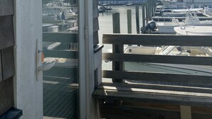 A wooden deck with a view of a marina and houses in the background. - Charming Studio / Cottage in Marina BHI & Shoals Club Available (Bald Head Island)