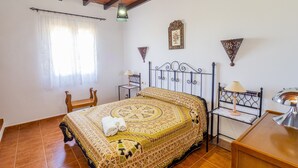 Une chambre à coucher comprenant un lit, une table de chevet, une chaise, une lampe et un élément décoratif mural.