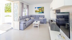 Ein modernes Wohnzimmer mit einem grauen Ecksofa, einem weißen Couchtisch und einem Flachbildfernseher.
