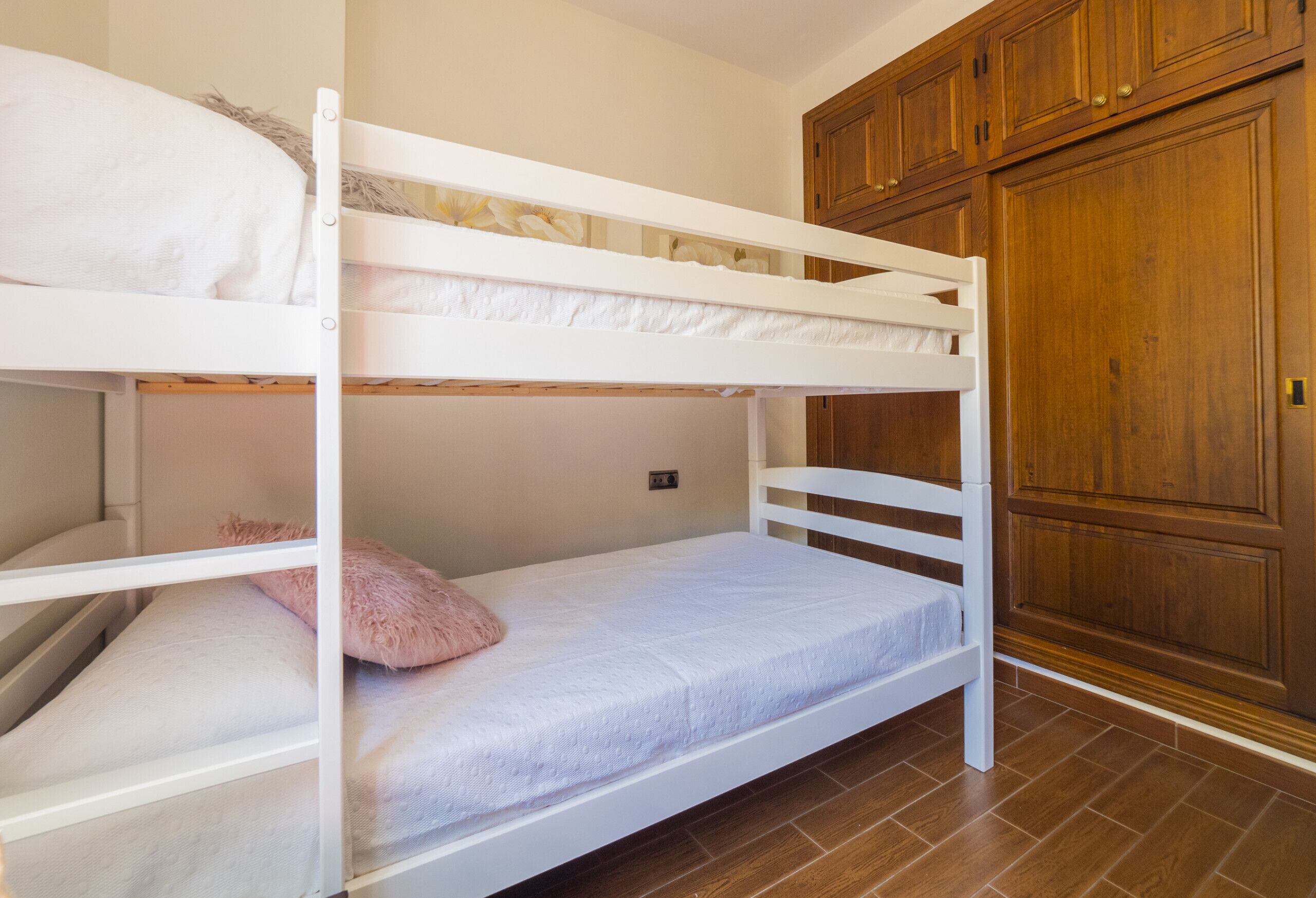 A bunk bed room with wooden cabinets and a tiled floor.