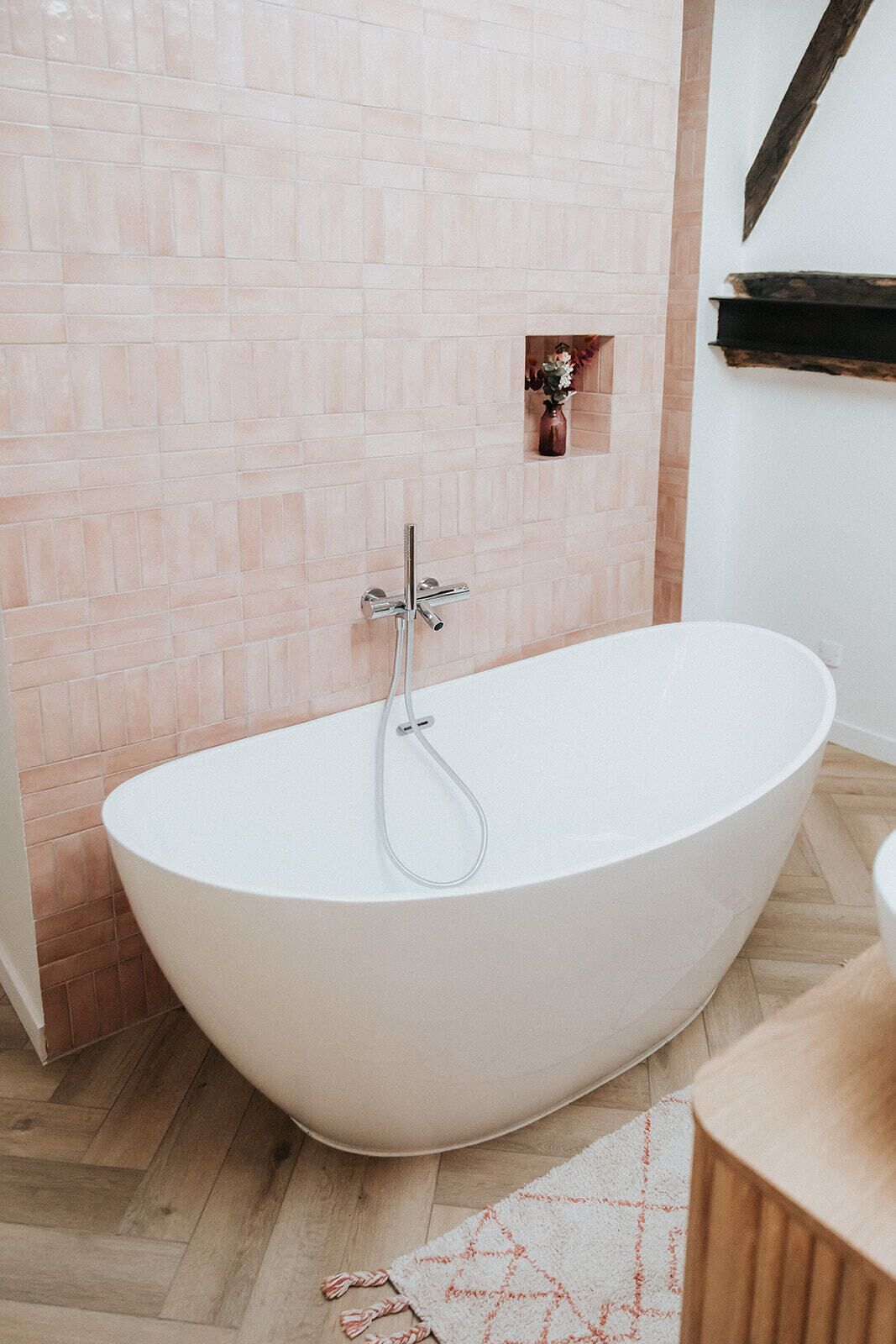 Un baño moderno con una bañera independiente, un revestimiento de azulejos y suelo de madera.