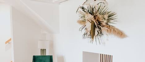 A modern living room with a green armchair, a yellow armchair, a round coffee table, and a hanging plant.