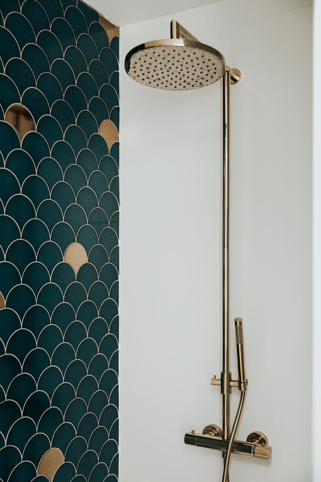 A shower with a gold-colored rain showerhead and a handheld shower attachment.