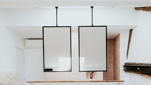 A minimalist bedroom with a bed, a wooden headboard, and a hanging light fixture. - Château La Grande Clotte (Lussac)