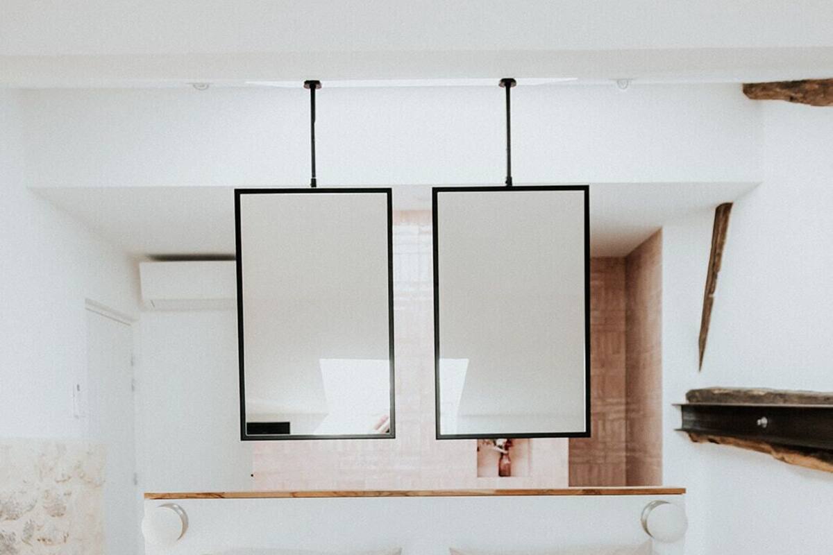 A minimalist bedroom with a bed, a wooden headboard, and a hanging light fixture.