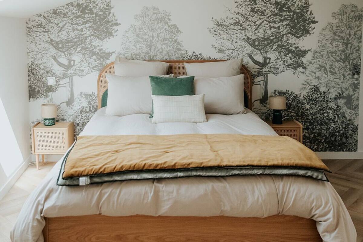 A bedroom with a wooden bed, a skylight, and a wall mural of trees.