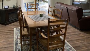 A dining area with a wooden table and chairs, a sofa, and a fireplace.