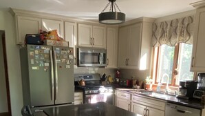 A kitchen with a central island, white cabinets, a microwave, and a stove.