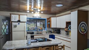 Une cuisine dotée d’un plan de travail en marbre, de chaises en bois, d’un réfrigérateur, d’un évier et d’armoires.