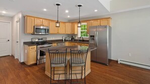 A modern kitchen with wooden cabinets, stainless steel appliances, and a central island with bar stools.