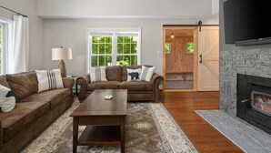 A living room with two brown leather sofas, a wooden coffee table, and a stone fireplace.