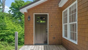 A wooden house with a front door, a window, and a porch.