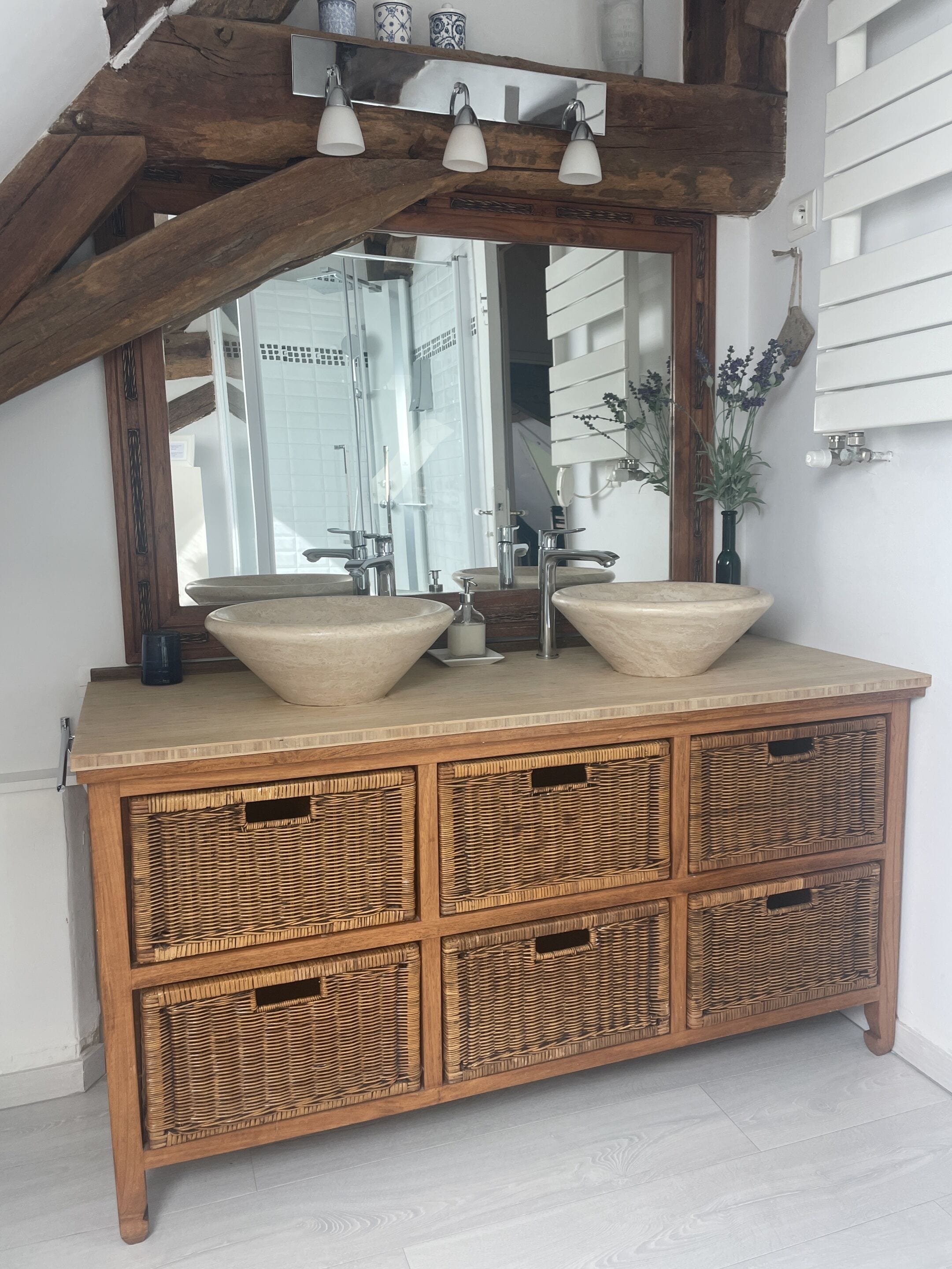 A wooden vanity with two large sinks, a mirror, and a ceiling light fixture.